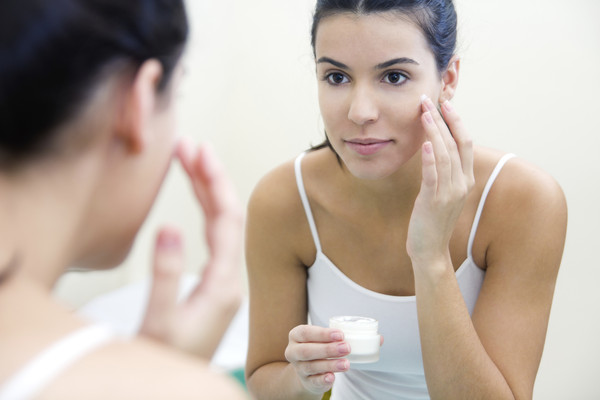 Body care. Woman applying cream on face